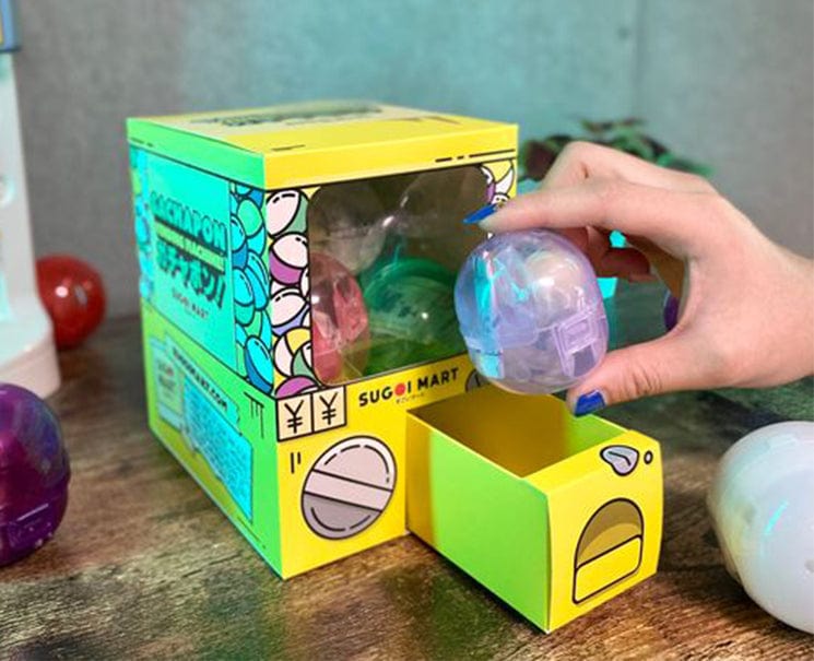 Sugoi Mart mini yellow colored gachapon box with purple capsule toy.